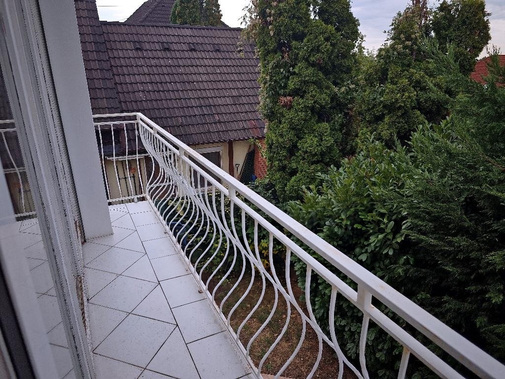 Csempézett erkély fém korláttal, kilátás a környező zöldre
